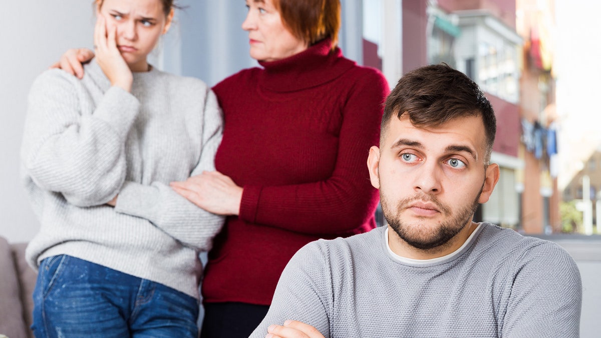 man looking dismayed as mother comforts daugther