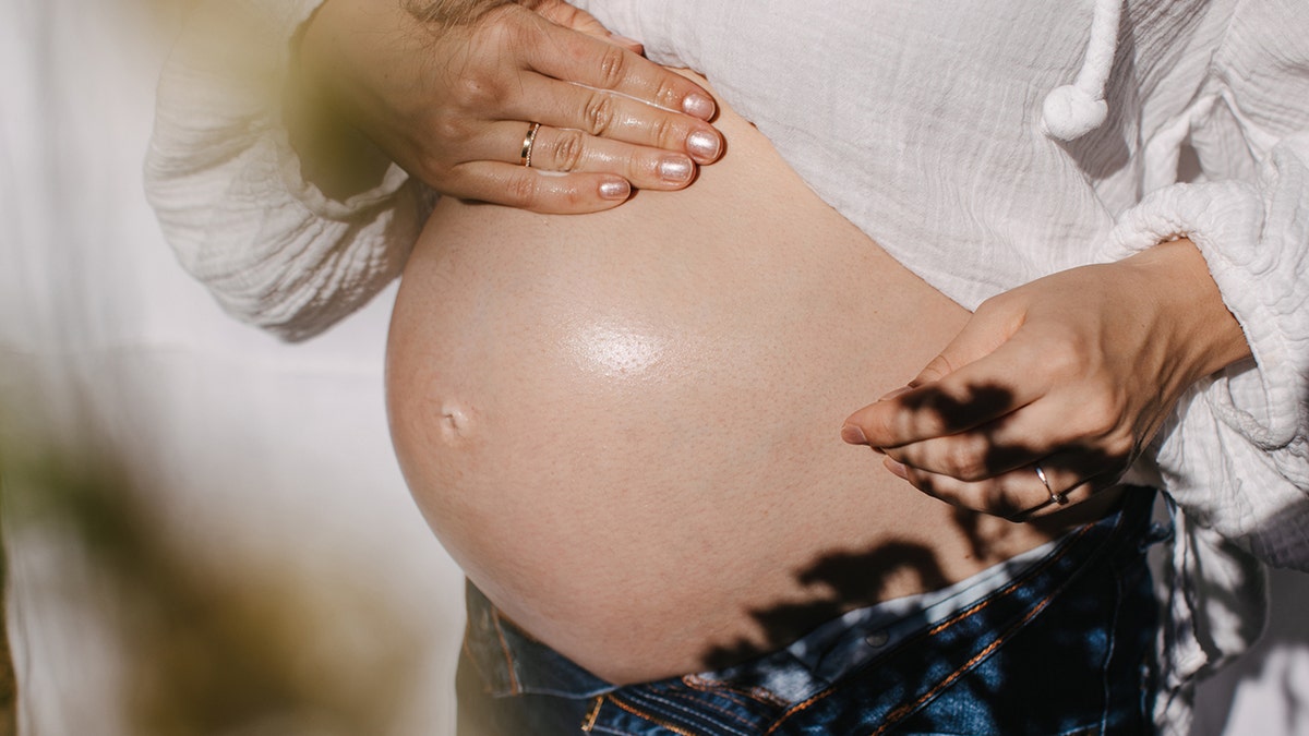 A pregnant woman rubbing her stomach with oil