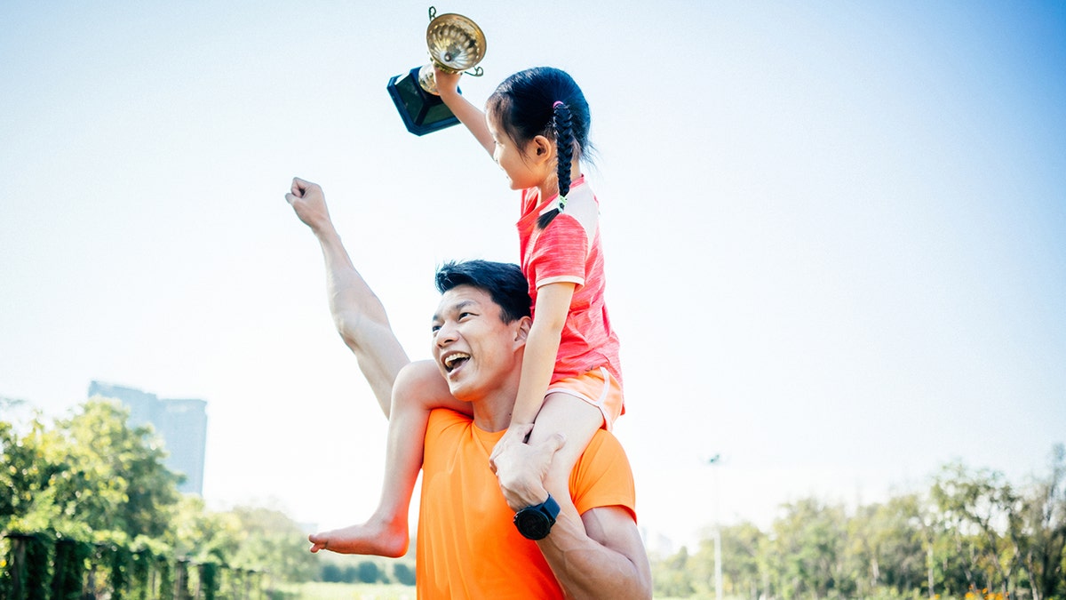 Father and daughter celebrating with trophy in hands