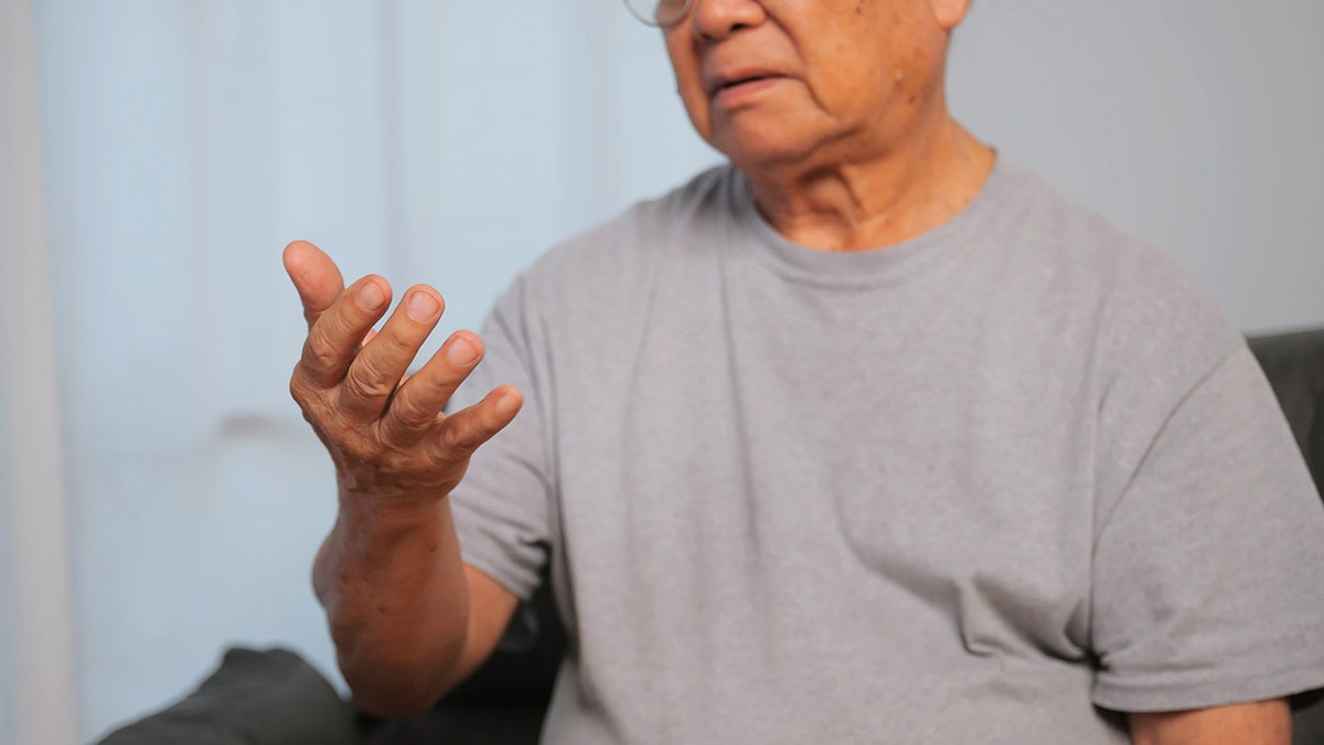 A mão de um homem idoso está tremendo por causa da doença de Parkinson