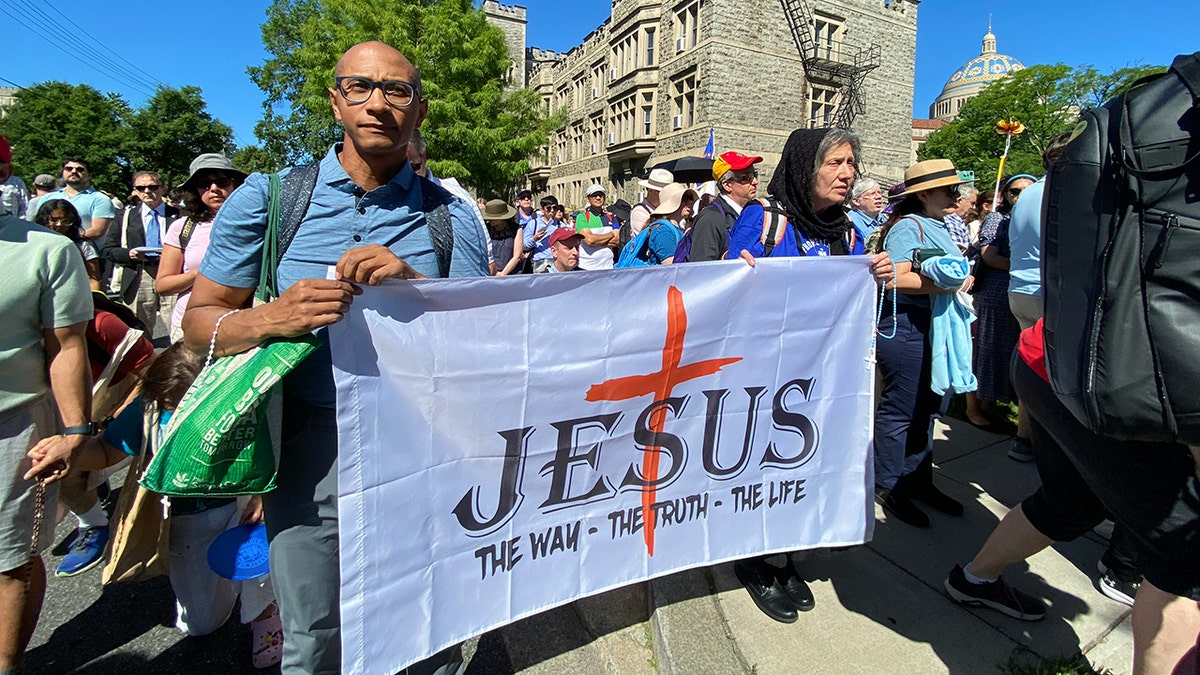A man and a woman holding a banner of Jesus