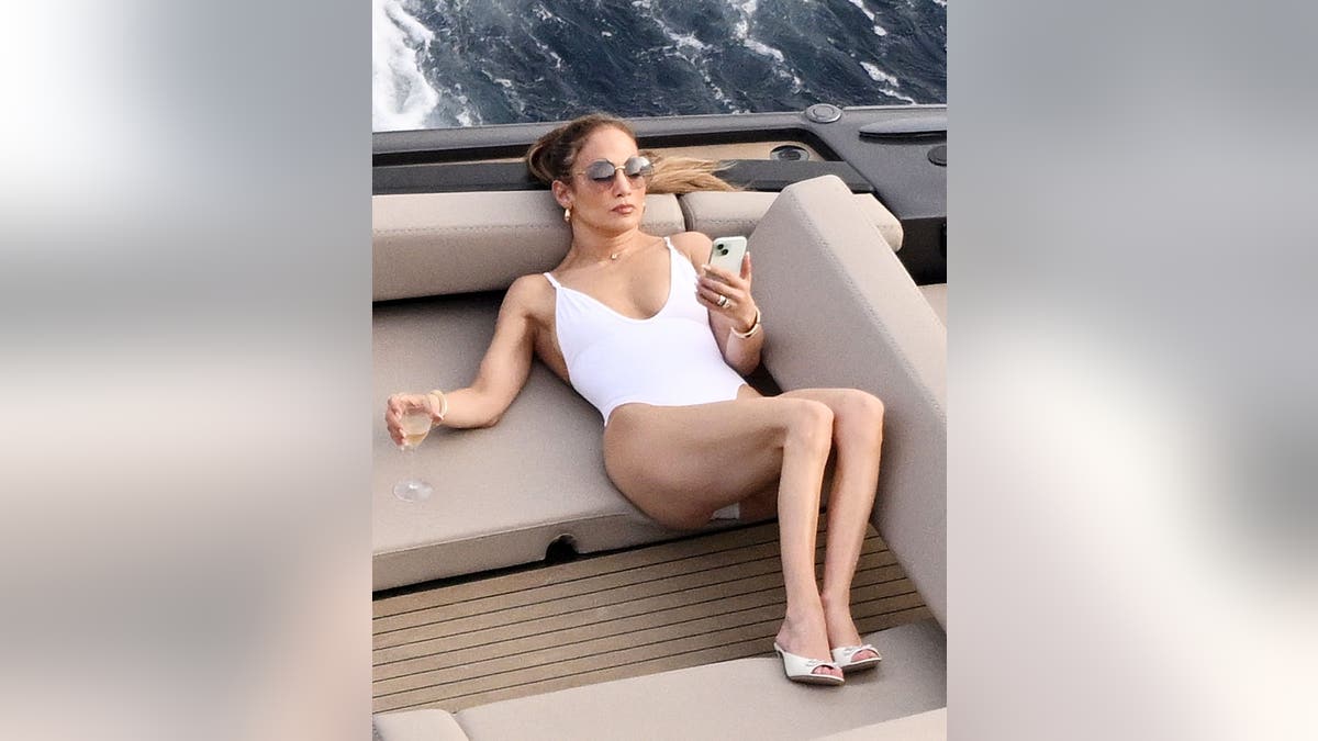 Jennifer Lopez patrzy na swój telefon komórkowy na statku we Włoszech