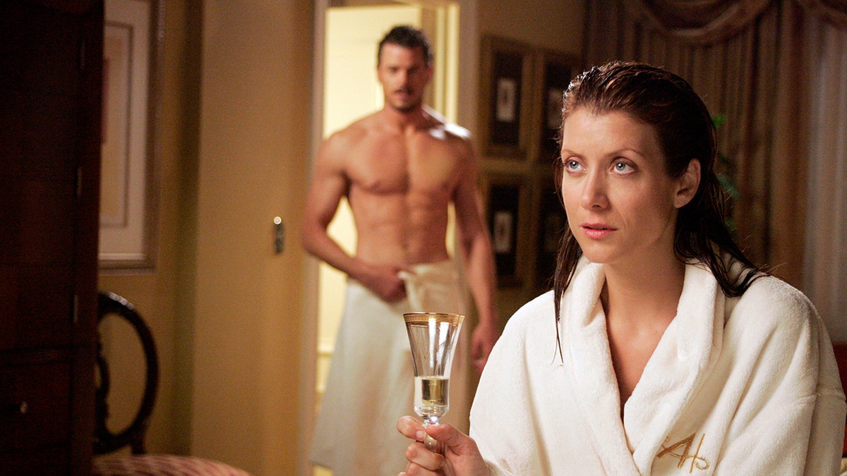 Eric Dane em nada além de uma toalha como Dr. Mark Sloan e Kate Walsh em um roupão segurando uma taça de champanhe como Dra. Addison Montgomery