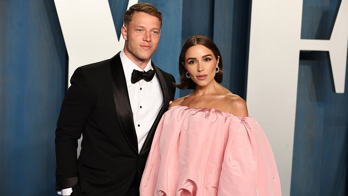 Christian McCaffrey in a classic tuxedo at the Vanity Fair after party with Olivia Culpo in a puffy baby pink off the shoulder dress