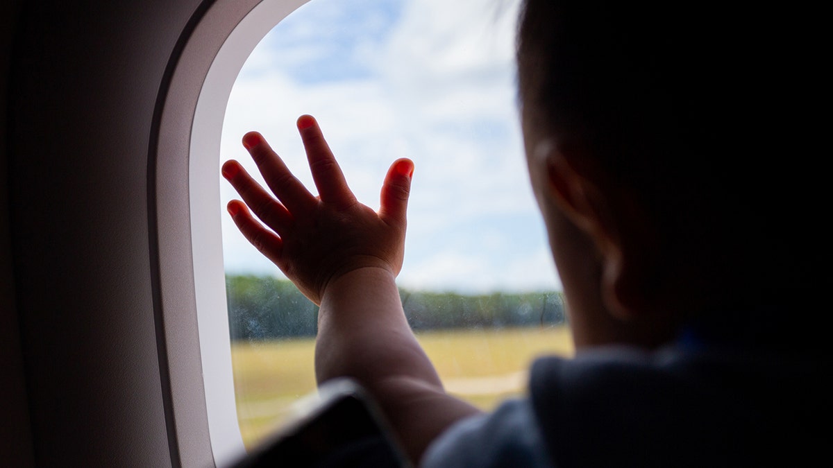 Baby touching airplane window