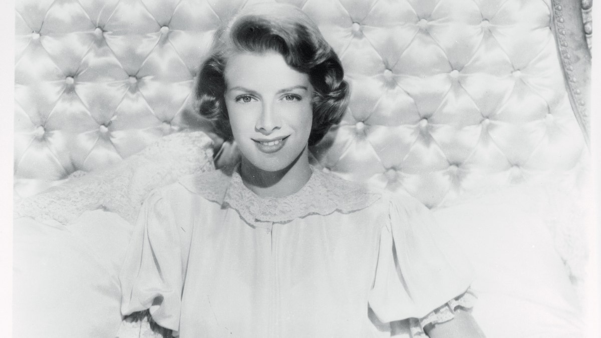 Black and white photo of Rosemary Clooney smiling on a bed