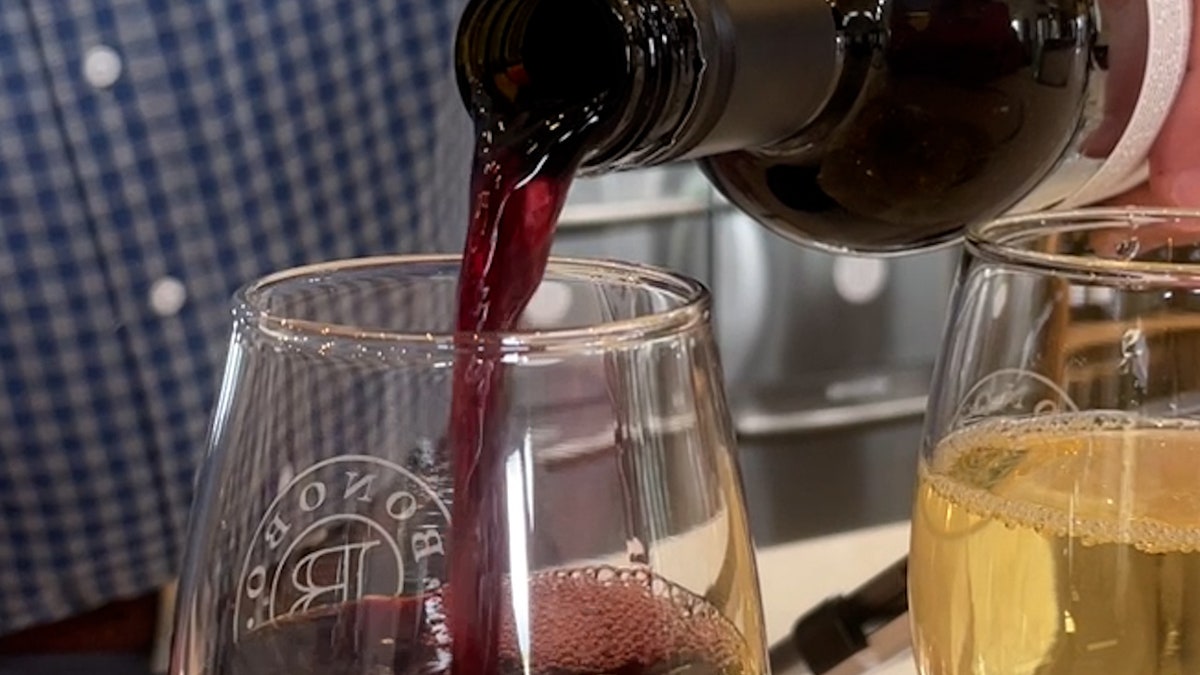 a red bottle of win is poured into a wine glass