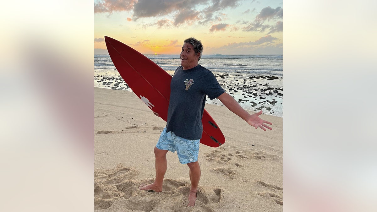 Tamayo Perry na praia com prancha de surf