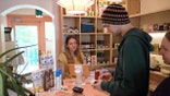 a woman checks some guys id at the checkout section of her NA bottle shop
