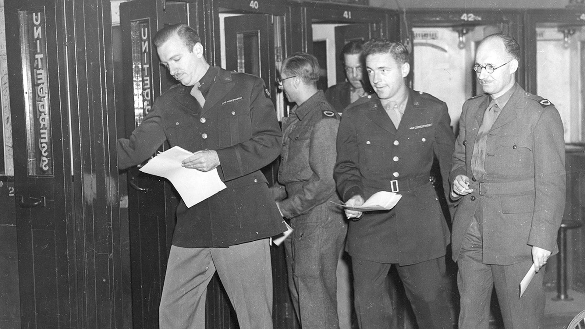Walter Cronkite, Frank Starr, Melvin K. Whiteleather, Robert Wilson and Alex Paton dash for the phone to transmit their news in Bloomsbury, England