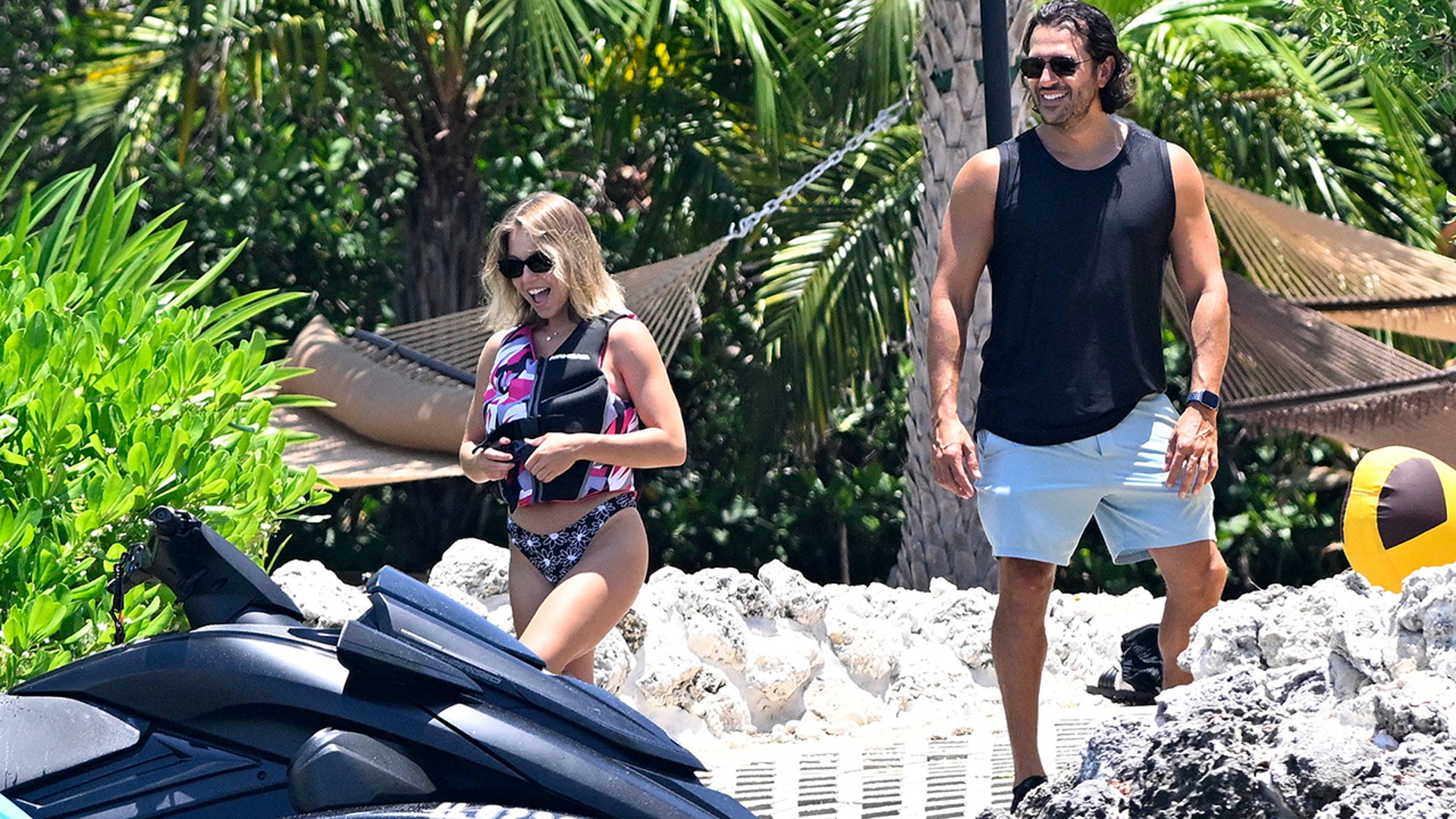 Sweeney excitedly approaches a jet ski, with her fiancé, Jonathan Davino, looking on.