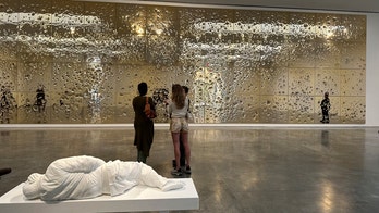 A bullet-riddled gold wall, fountain of a man urinating comprise artist Cattelan's latest piece