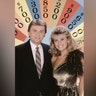 Pat Sajak and Vanna White in front of a vintage board for the game show