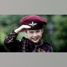 William looks into the camera and salutes while in an army uniform in 1986.