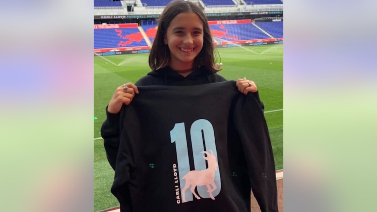 Jocelyn Walters holds up a Jersey at a soccer stadium