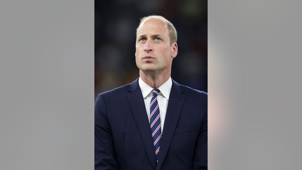 Prince William in a navy blazer with a striped blue and red tie.