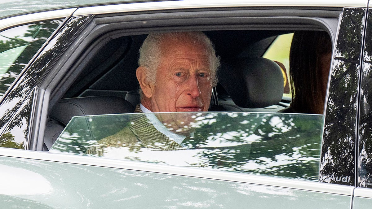 El rey Carlos mirando desde la ventanilla de su coche.