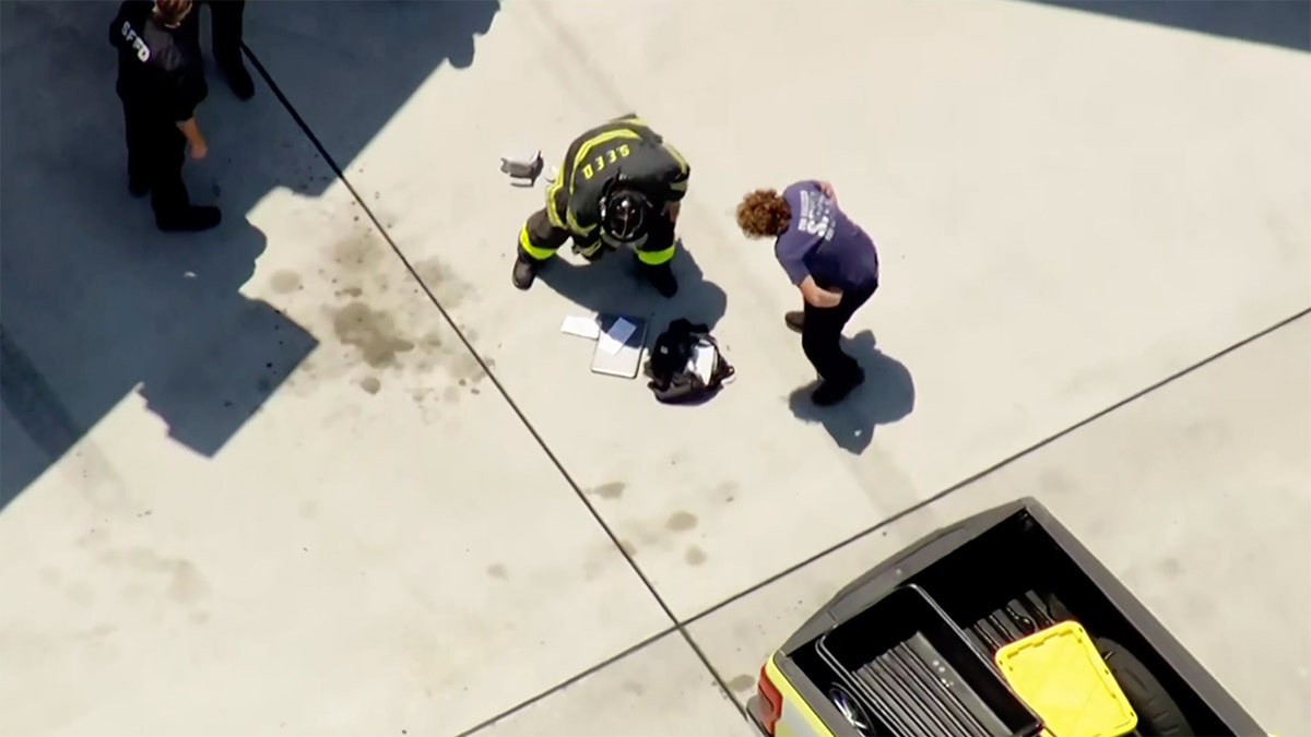 An aerial shot of two firemen extinguishing a smoking laptop