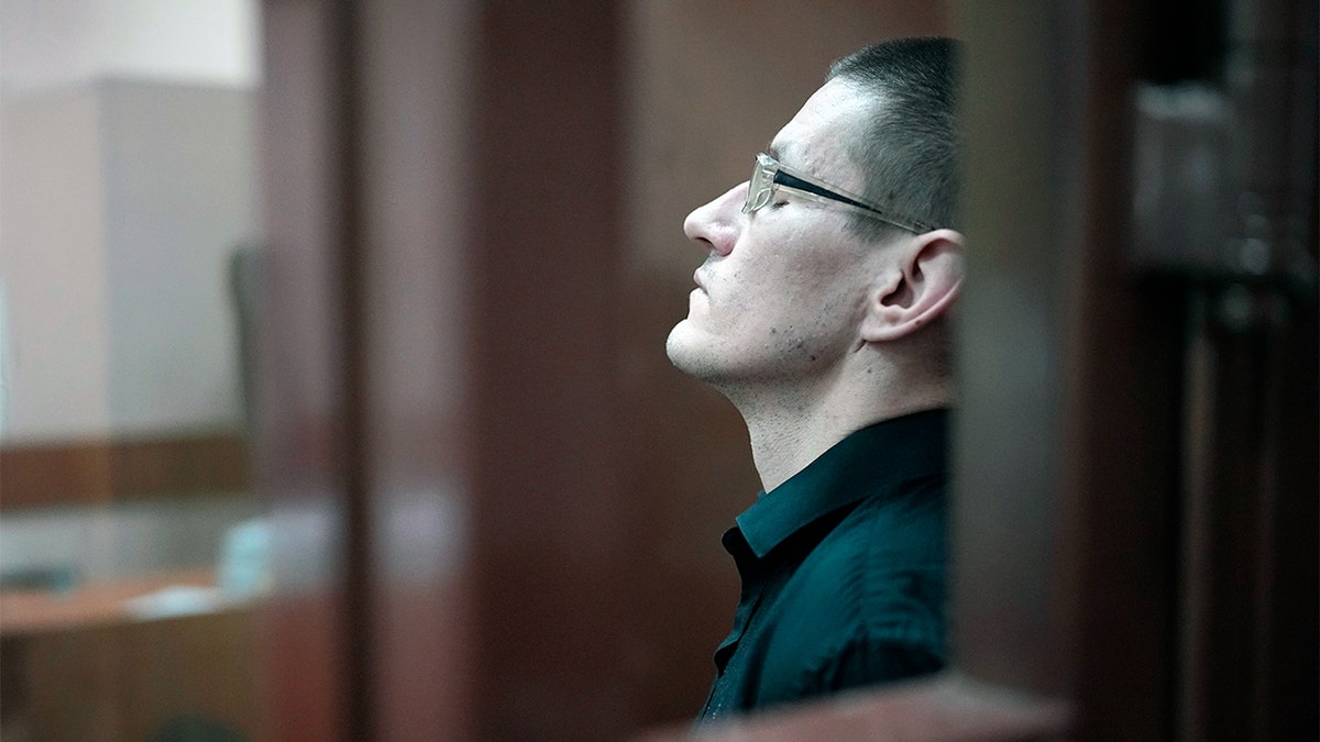 Robert Woodland sentado en una jaula de cristal en un tribunal ruso