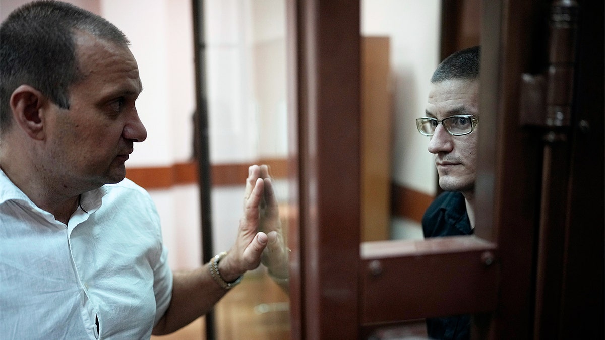 Robert Woodland sentado en una jaula de cristal en un tribunal ruso
