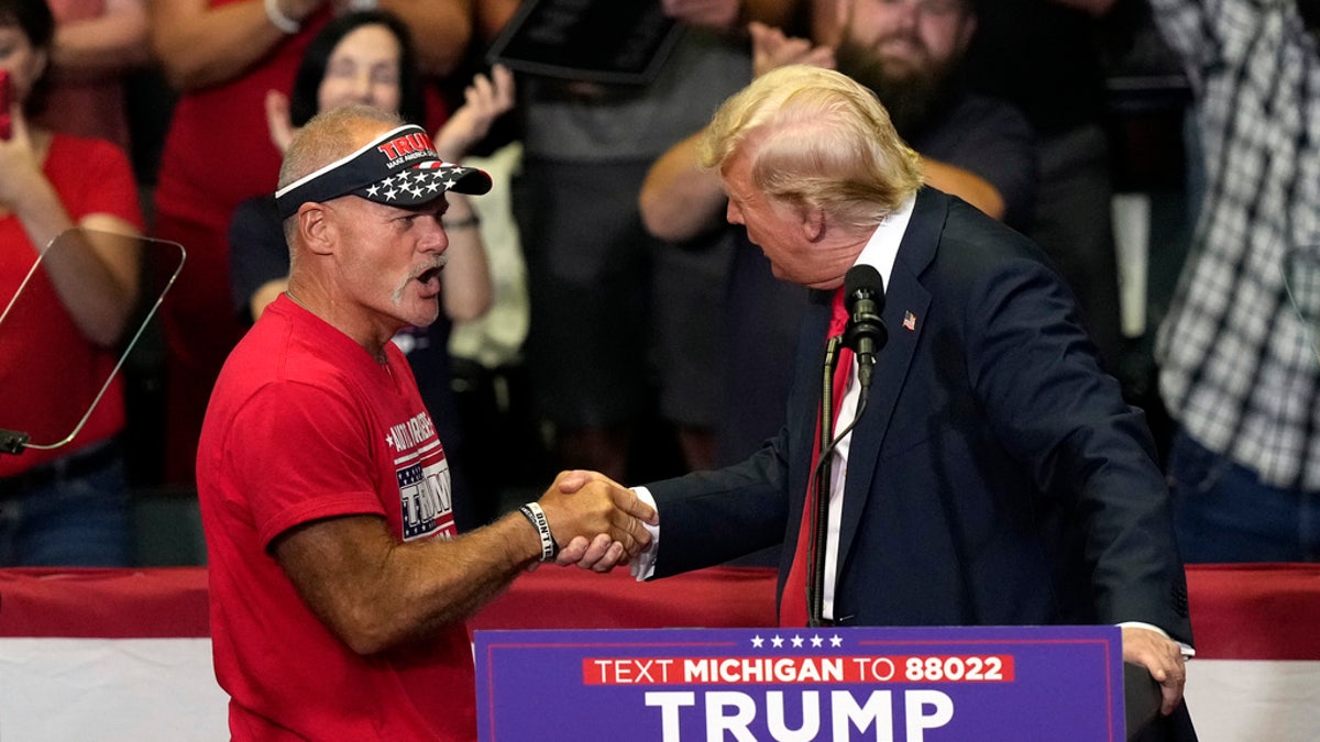 Republican presidential candidate former President Donald Trump, right, shakes hands with an autoworker on stage at a campaign event Saturday at Van Andel Arena in Grand Rapids, Mich.