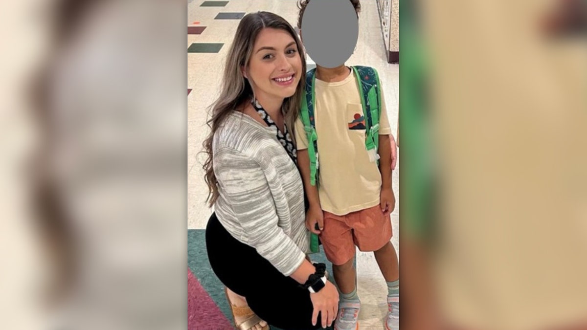Alexa Stakely poses with a child in a school hallway