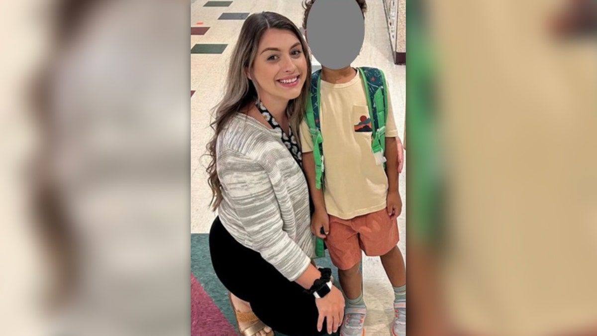 Alexa Stakely posa con un niño en el pasillo de una escuela