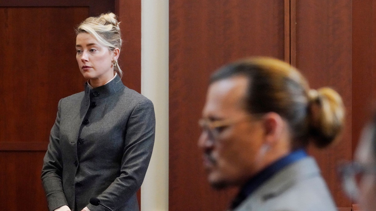 Amber Heard and Johnny Depp sit in a courtroom