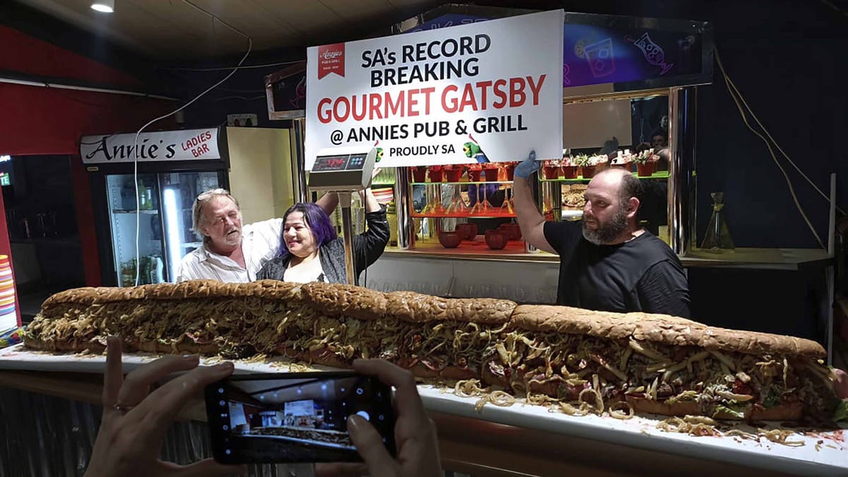 Annie Redelinghuys y Michael Steyn posan con el submarino gigante de Gatsby en el Annie's Ladies Bar de Sudáfrica.