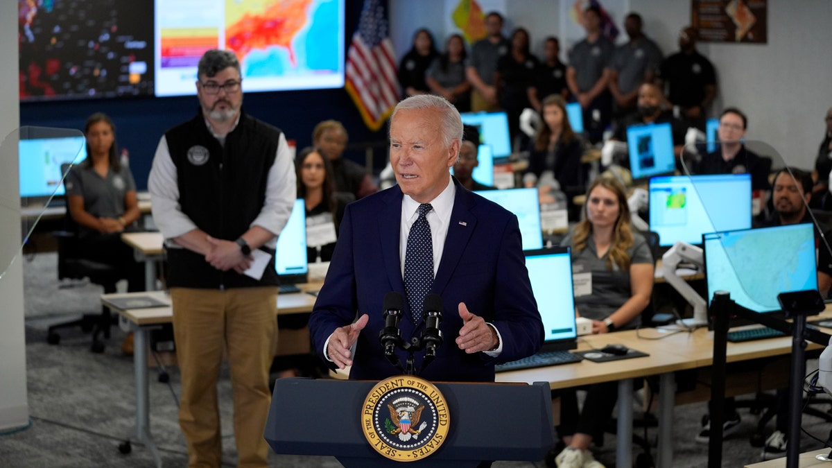 O presidente Joe Biden está em um pódio no Centro de Operações de Emergência de DC em frente a um mapa do país exibindo dados de calor.