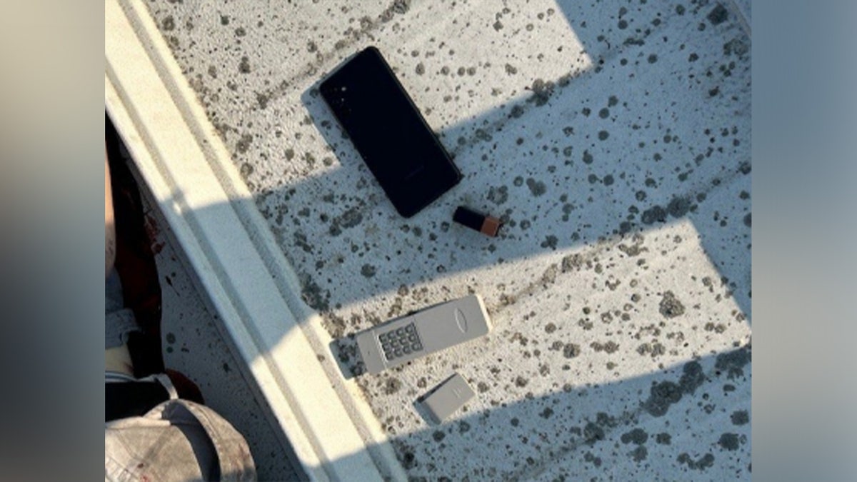 An evidence photo of a cell phone and transmitting device found alongside Thomas Crooks