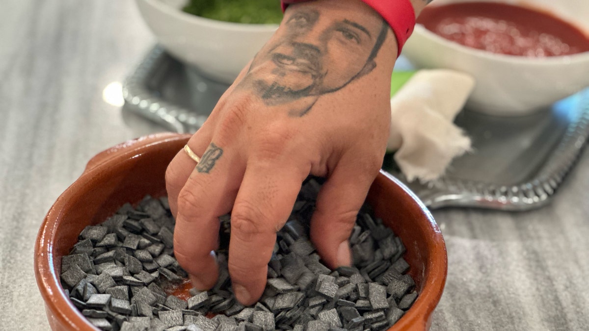 Christos Bisiotis's hand is seen reaching into a bowl for squid ink hilopites from his Bellita Pasta line.