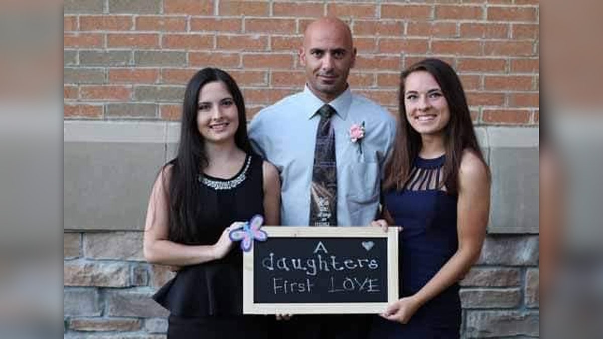 Comperatore and daughters hold a sign calling their father "first love"