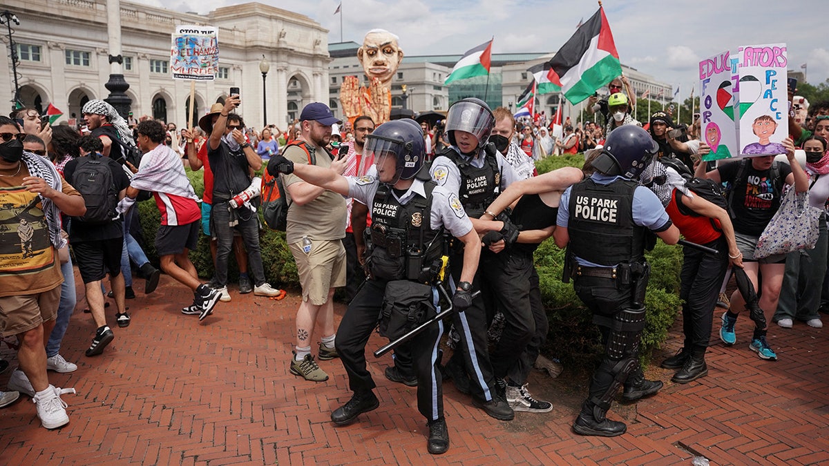 Agentes de la Policía de Parques de EE.UU. reaccionan mientras retiran a un manifestante esposado en una protesta propalestina