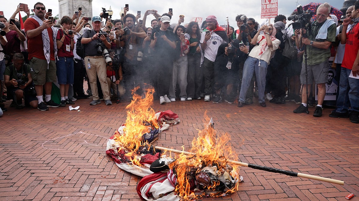 Demonstrators gather around a burning U.S. flag and effigy during a pro-Palestinian protest