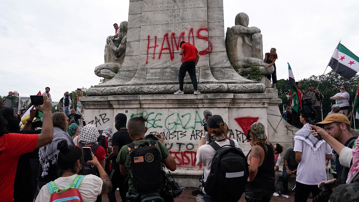 A pro-Palestinian demonstrator sprays graffiti on Christopher Columbus Memorial Fountain at Union Station