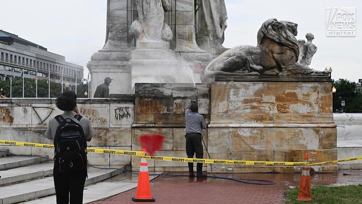 Workers clean up graffiti on the fountain in front of the entrance to Union Station in Washington D.C.