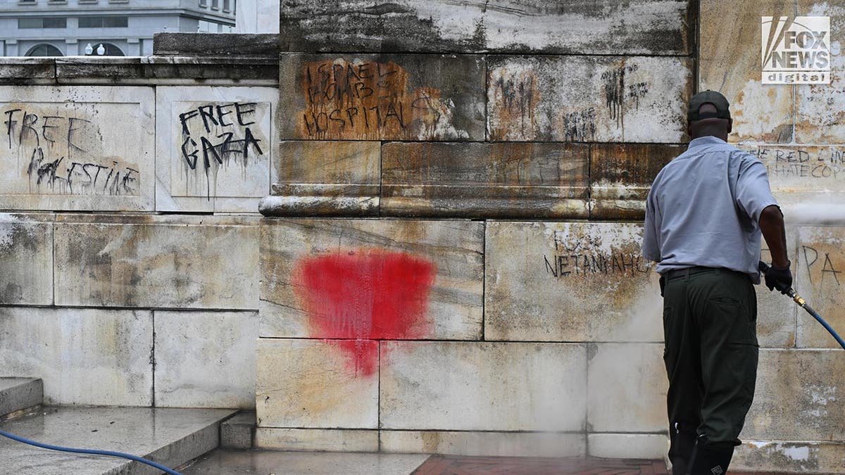 Workers clean up graffiti on the fountain in front of the entrance to Union Station