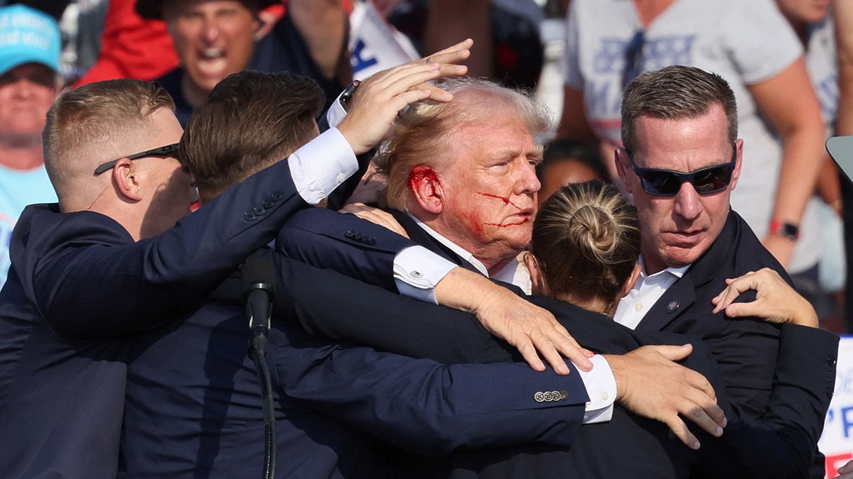 Donald Trump hace un gesto con la cara ensangrentada mientras se escuchan varios disparos durante un mitin de campaña