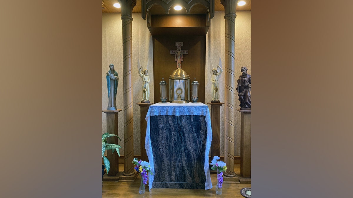 An altar displays a crucifix and saints in a Catholic church