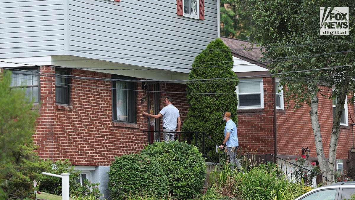 Two men knock on a door