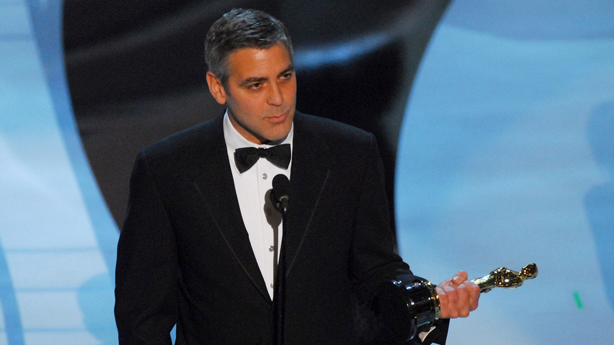 George Clooney on stage holding his Oscar