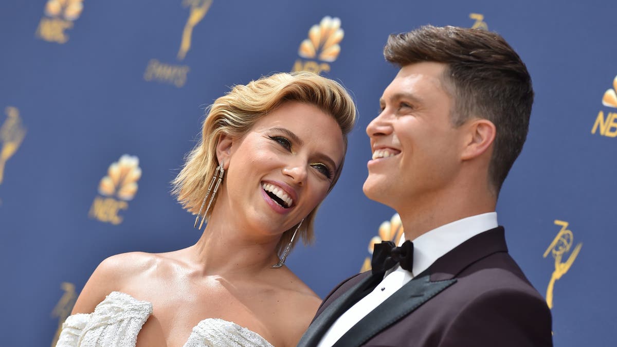 Colin Jost and Scarlett Johansson smiling on red carpet
