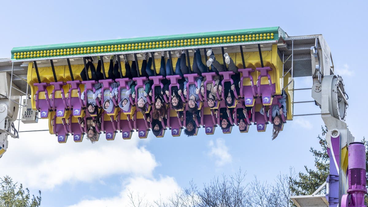 Gente boca abajo en una atracción de un parque de atracciones llamada Perseguidor de la Luna