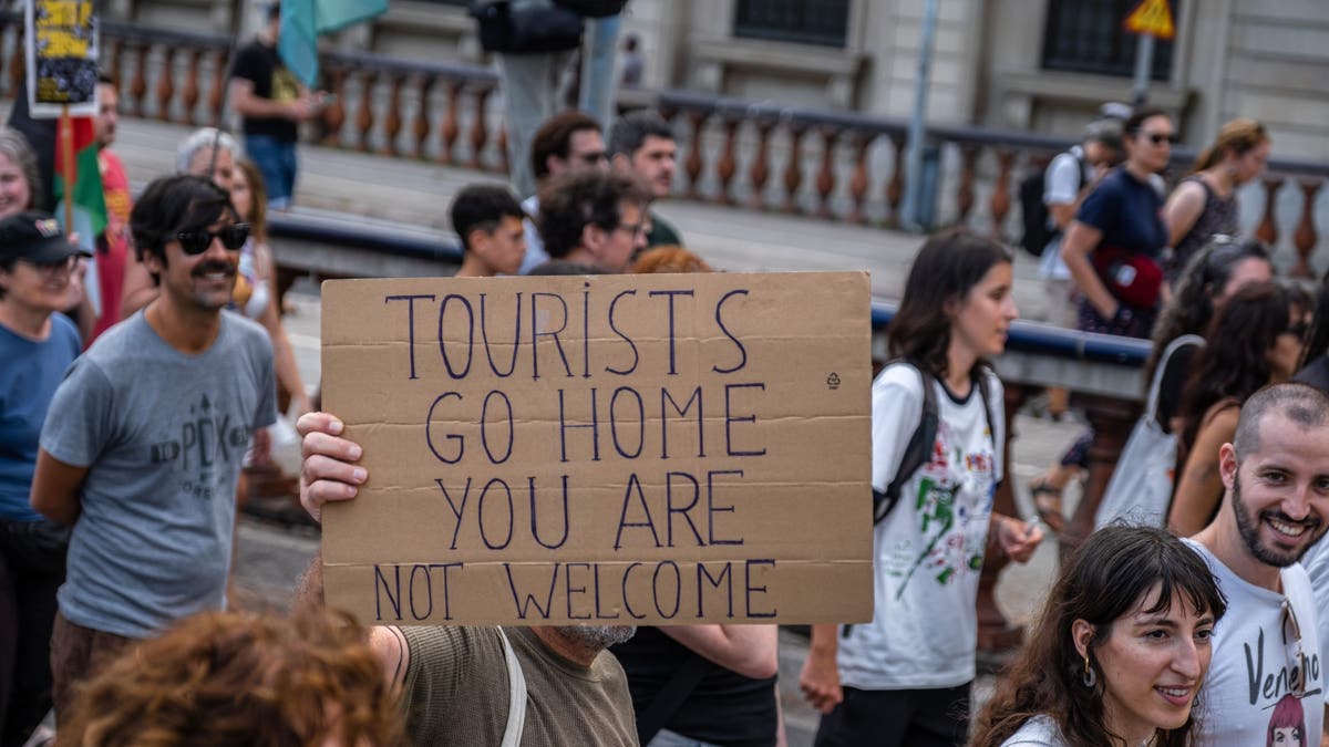 anti-tourist protest with "tourists go home" sign center