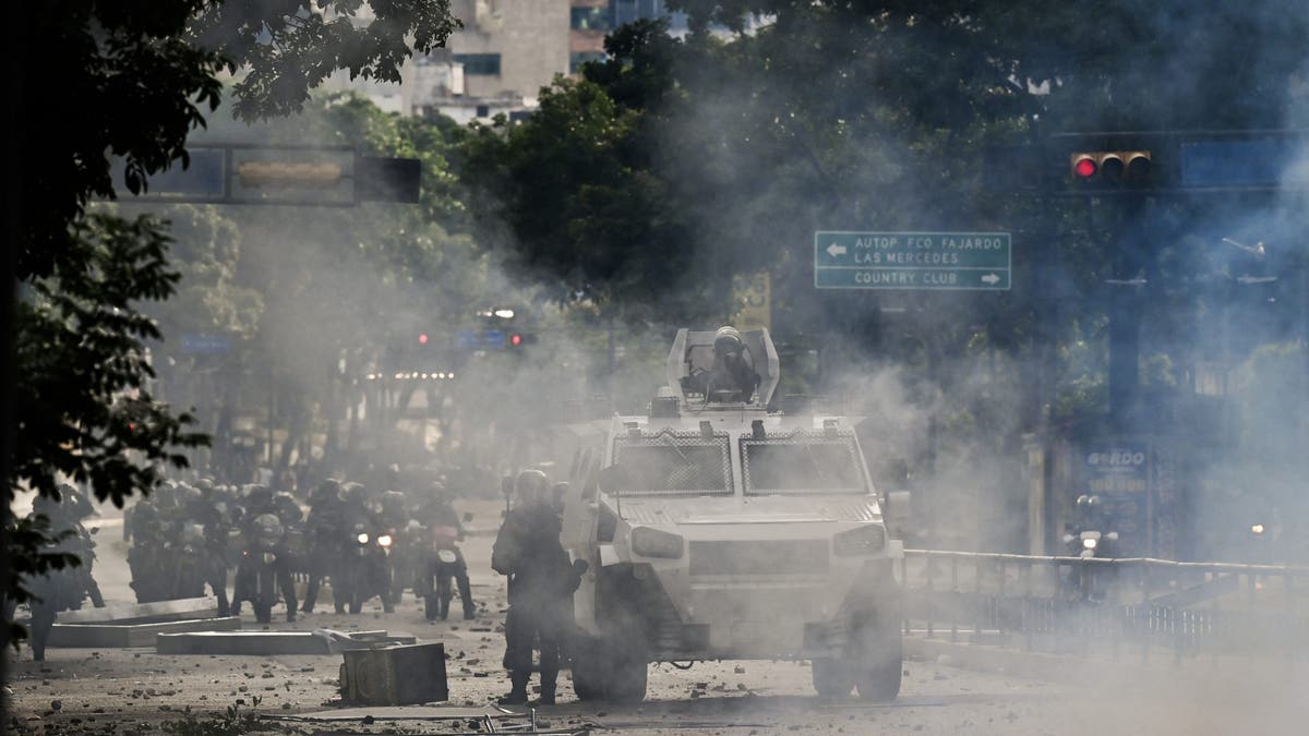 Un coche blindado de la policía atraviesa gases lacrimógenos durante una protesta contra el presidente venezolano Nicolás Maduro en Caracas, el 29 de julio de 2024, un día después de las elecciones presidenciales venezolanas.