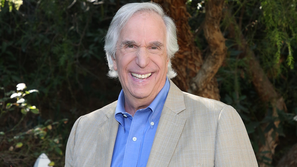 Henry Winkler smiling wearing a beige blazer and a light blue shirt.