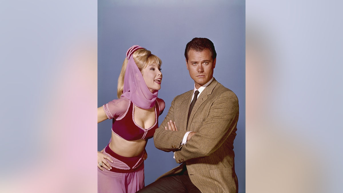 Barbara Eden hace una mueca divertida a Larry Hagman mientras parece molesta.