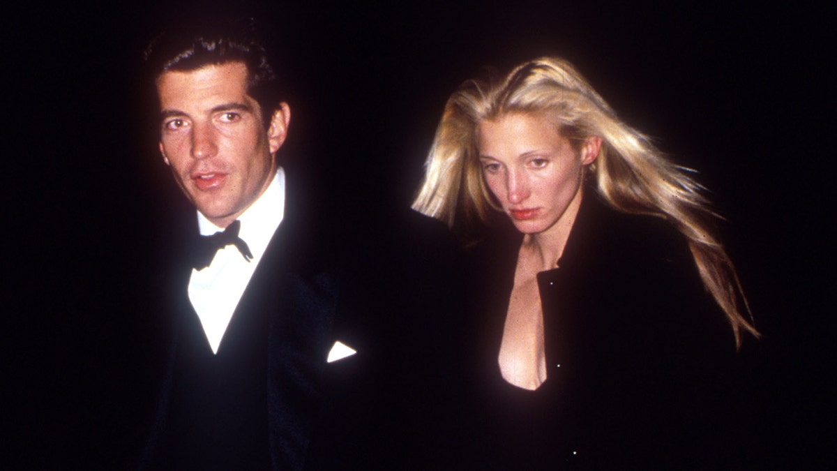 Carolyn Bessette-Kennedy looking tense in black next to John F. Kennedy Jr. in a tux.