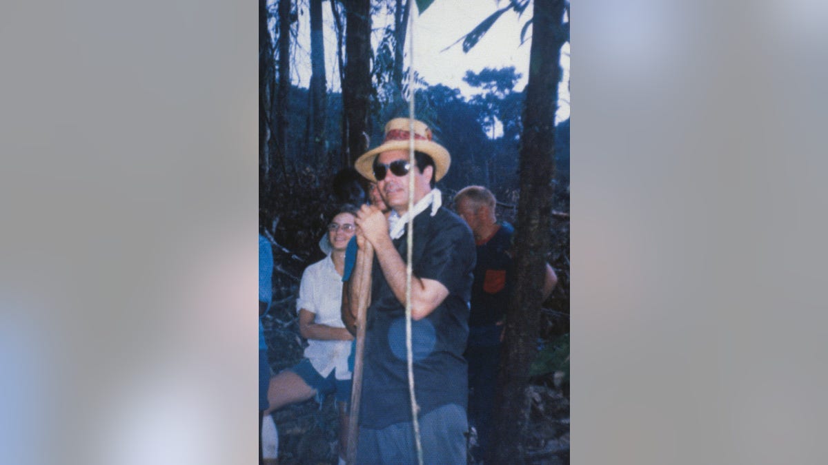 Jim Jones wearing a straw hat and holding a walking stick.
